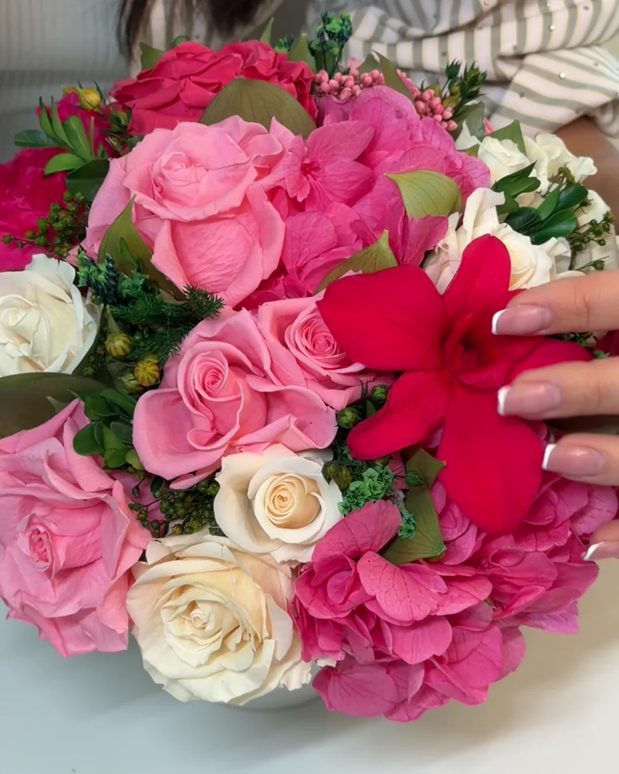 A florist adjusting a pink IN BLOOM arrangement
